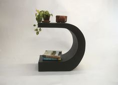 a black shelf with books and plants on it