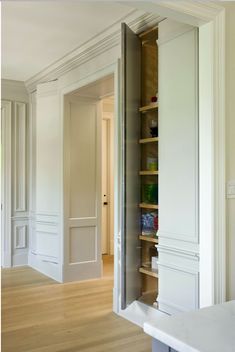 an open closet in the corner of a room with white walls and wood flooring