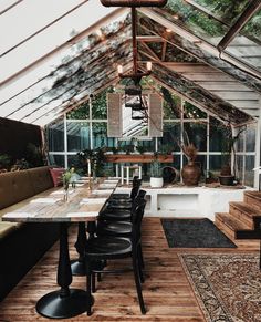 an indoor dining area with wooden flooring and glass walls, surrounded by greenery