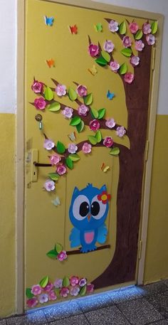 the door is decorated with paper flowers and an owl sitting on a branch in front of it