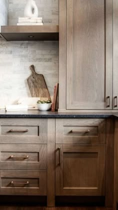 a kitchen with wooden cabinets and black counter tops, including a cutting board on top of the cabinet doors