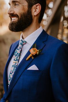 a man with a beard wearing a blue suit and flowered boutonniere