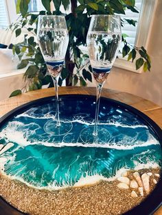 two wine glasses sitting on top of a wooden table next to a potted plant