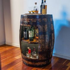 a wooden barrel filled with liquor bottles on top of a hard wood floor