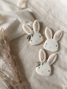 three decorated cookies are laying on a table cloth with dried grass in the foreground