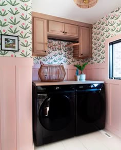 a washer and dryer in a pink laundry room with floral wallpaper on the walls