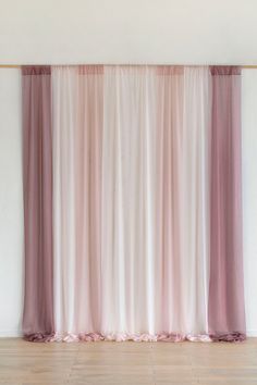 an empty room with pink curtains and wooden floors