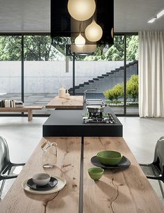 a table with plates and bowls on it in front of a large glass window that has stairs leading up to the second floor