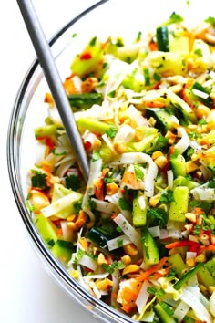 a salad with carrots, celery, and other vegetables in a glass bowl