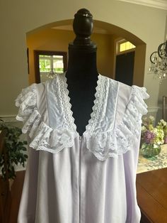 A warm and cozy zip front robe by Beth Michaels.  The robe is the palest of  lavender in color with contrasting white ruffle lace trim and satin on the bodice. V-neck with zip front.  Ruffle cuffs.  In good vintage condition with no rips or stains.  The bust measures 21.5 inches from armpit to armpit laying flat and 51 inches from shoulder to hem.  Made in the USA.  Please examine the pics, feel free to ask questions. Spring Lace Trim Robe For Bedtime, Feminine Fitted Robe With Lace Trim, Fitted Feminine Robe With Lace Trim, Spring Bedtime Robe With Lace Trim, Long Sleeve Lace Trim Robe For Bedtime, Vintage Ruffled Nightgown For Loungewear, Vintage Nightgown With Ruffles For Loungewear, Daywear Lace Robe With Lace Trim, Lace Trim Loungewear Robe