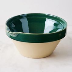 two green and white bowls sitting next to each other on top of a marble counter