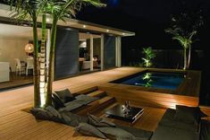 an outdoor living area with a pool at night