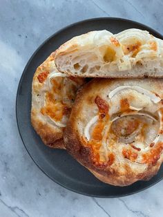 two pieces of bread sitting on top of a black plate with cheese and onions in it