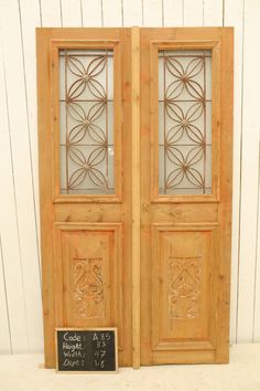 two wooden doors with glass panels and a chalkboard on the outside wall next to each other