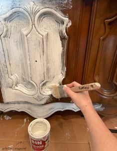 a person is painting a piece of furniture with white paint