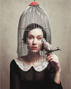 a woman holding a bird in a cage with the word love written on her face