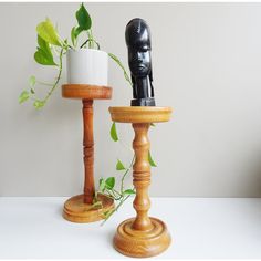 two wooden candlesticks with one candle holder holding a plant