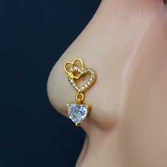 an earring with a heart shaped diamond hanging from it's side, on top of a mannequin