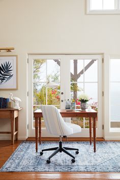 a chair sitting on top of a blue rug in front of a desk and window