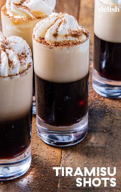 three glasses filled with drinks sitting on top of a wooden table