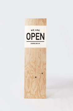 a wooden sign that says, we are open come on in black and white lettering