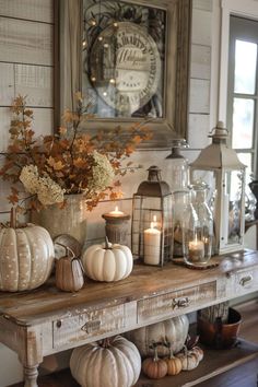 a wooden table topped with lots of white pumpkins and other fall decorating items