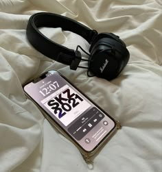 an mp3 player and headphones laying on top of a white sheet covered bed next to each other