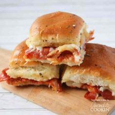 two sandwiches cut in half sitting on top of a cutting board with cheese and sauce