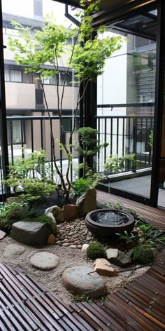 a small garden with rocks and trees in the center, on top of a wooden deck