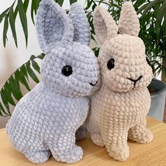 two crocheted stuffed animals sitting next to each other on top of a table