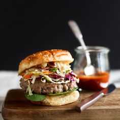 a hamburger sitting on top of a wooden cutting board next to a jar of ketchup