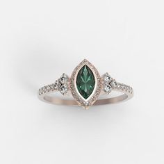 a ring with an emerald and white diamonds on it, set in rose gold plated sterling