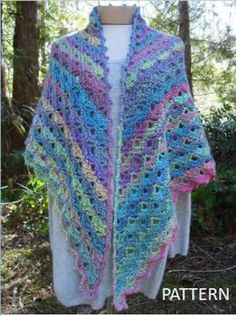 a crocheted shawl is shown on a mannequin dummy in the woods