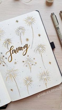 an open notebook with the word january written in gold on it next to some markers and crayons