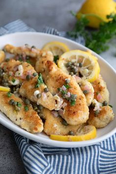 a white bowl filled with chicken and lemon slices