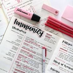 a pink pen sitting on top of an open notebook next to some writing paper and pens