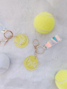 three tennis balls and two keychains on a white surface