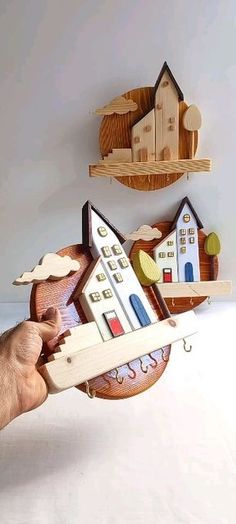 a hand holding a wooden model of a house