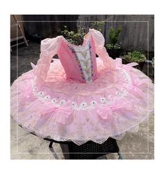 a pink and white dress sitting on top of a table next to a planter