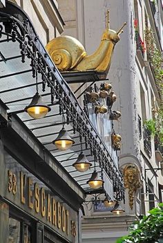 a gold snail sculpture on the side of a building with lights hanging from it's balconies