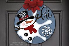 a door hanger with a snowman on it and a red bow hanging from the top