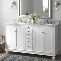 a white bathroom vanity with two sinks and a large mirror above it, in front of a striped rug