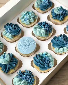 twelve cupcakes with blue frosting in a box