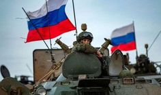 a man sitting on top of a tank in front of a flag and other flags