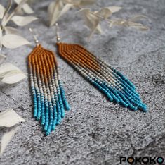 a pair of earrings with beads hanging from it's earwires next to some leaves