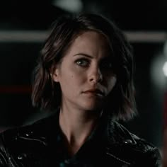 a close up of a person wearing a leather jacket and looking at the camera with an intense look on her face