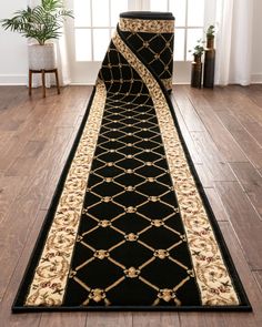 a black and gold runner rug on the floor in front of a window with potted plant