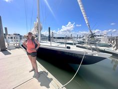 a woman standing on the dock next to a boat