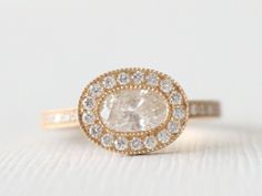 an engagement ring with a white diamond surrounded by small round brilliant cut diamonds in yellow gold