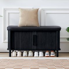 a black bench with shoes on it in front of a white wall